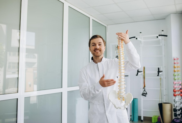 A vertebrologist holds a model of the spine in his hand